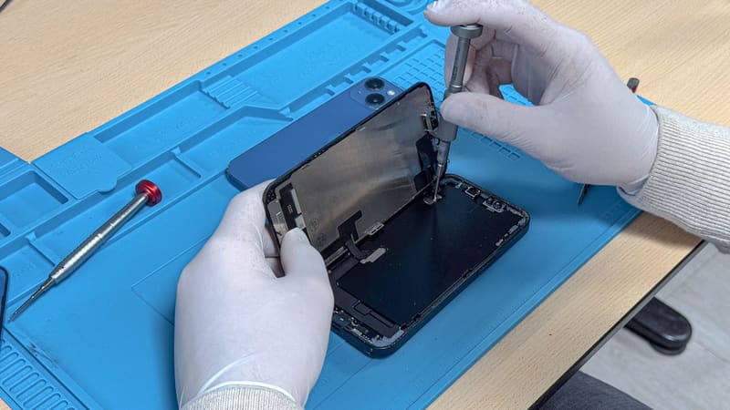 Met handschoenen een iPhone openen: het scherm klapt open op de blauwe werkmat
