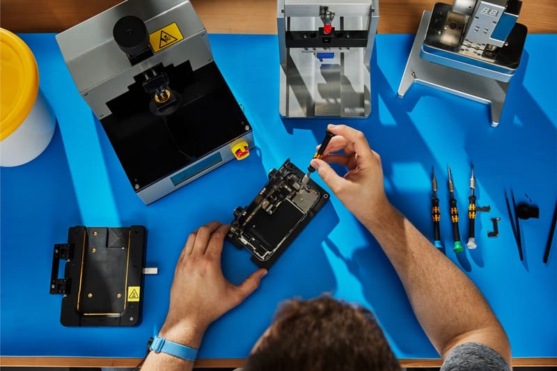 Bovenaanzicht van een werkbank met reparatieapparatuur en een geopende telefoon
